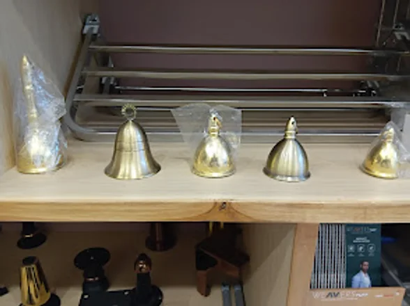 Brass bell-shaped knobs and fittings arranged on a wooden display shelf.