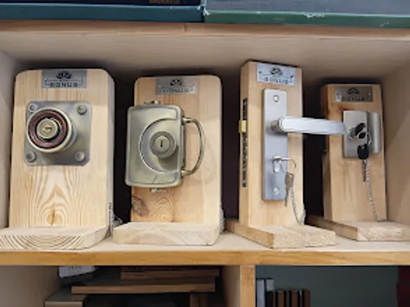 Door locks and latches mounted on wooden display blocks on a showroom shelf.