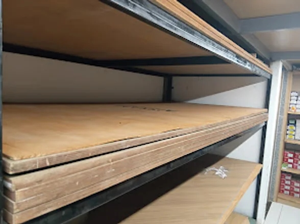Plywood boards stacked flat on steel racking inside the Pavan Decor showroom.